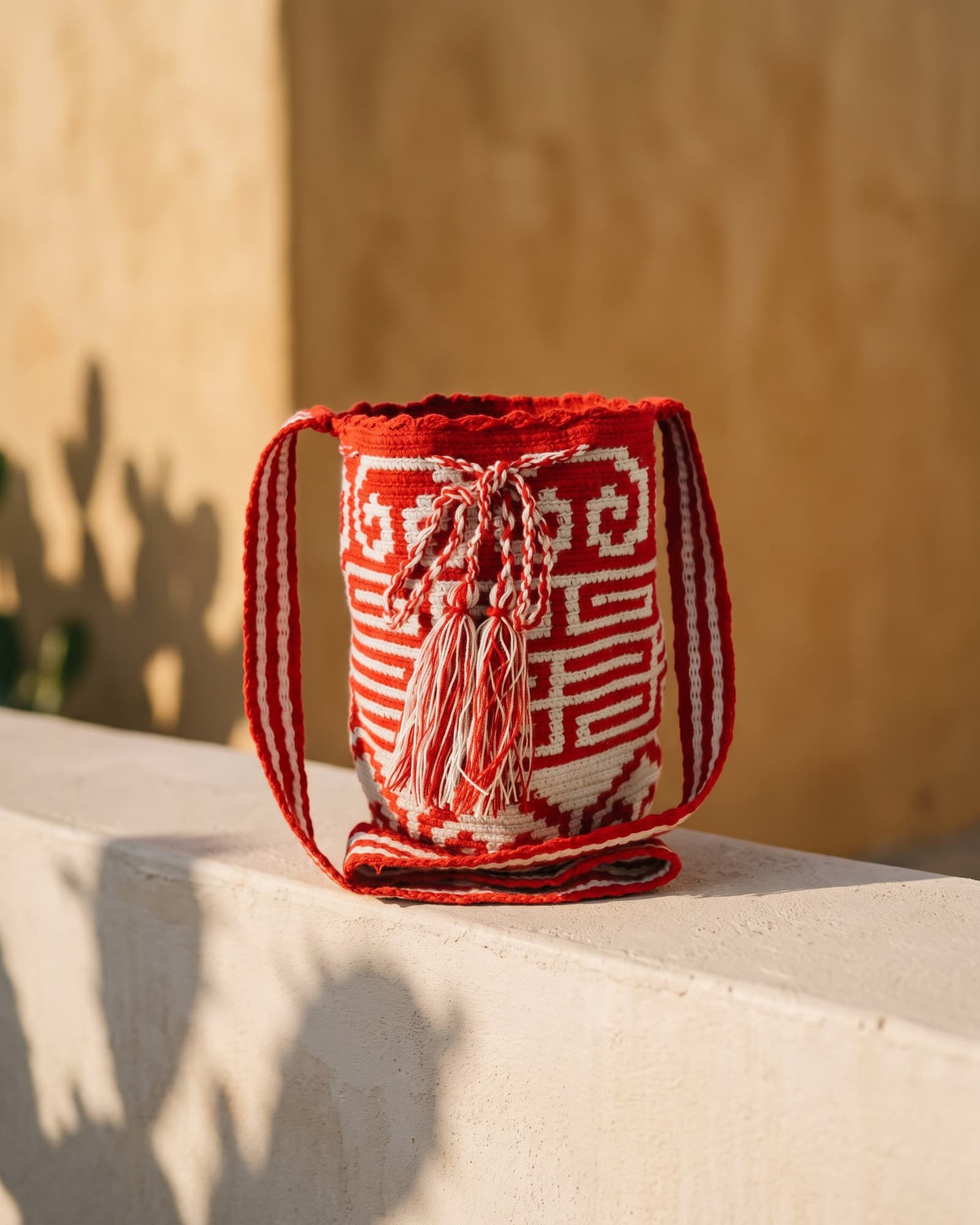 Handgewebte Wayuu-Mochila mit rot-weißer Greca auf warmem Leinen