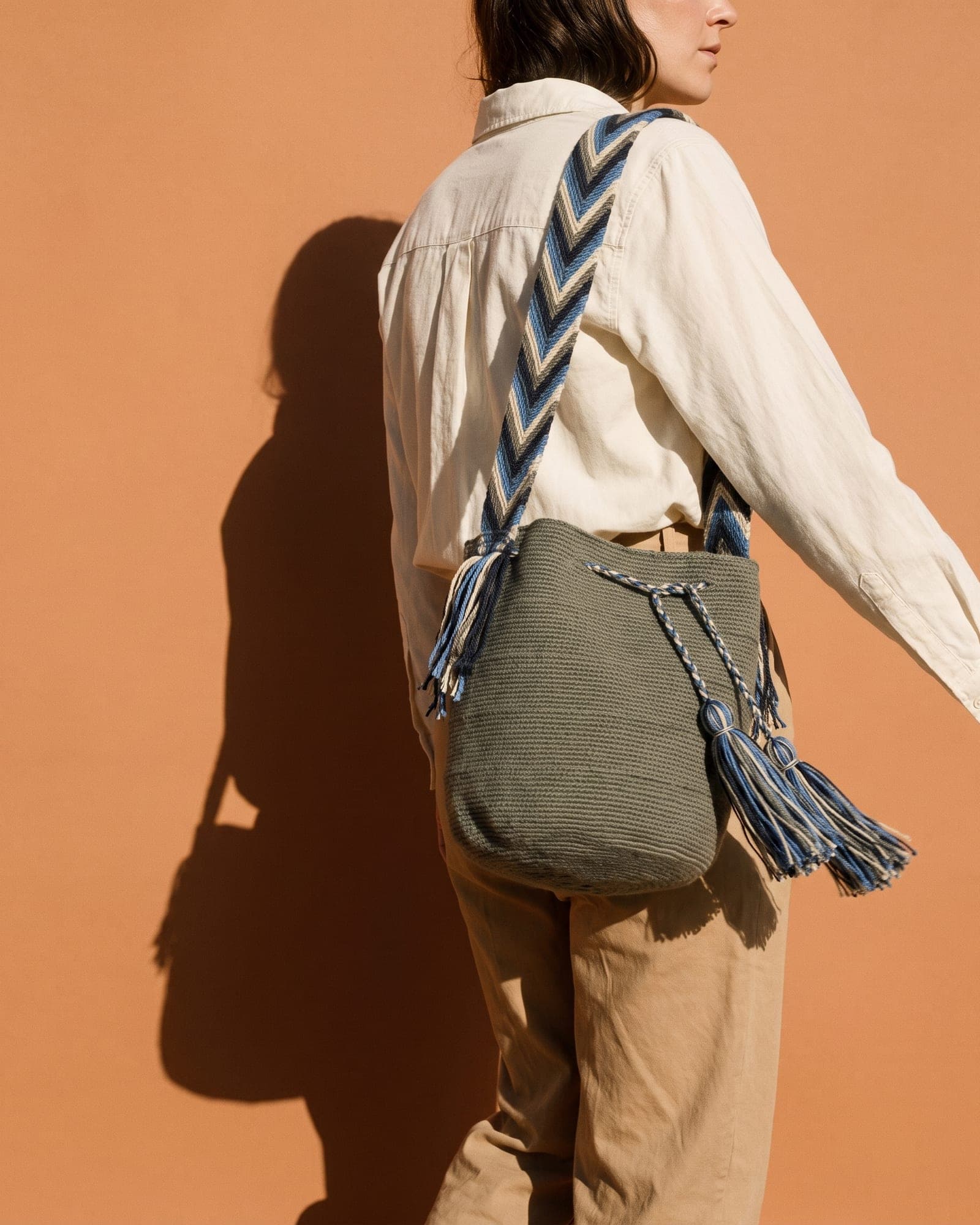 Die olivgraue Mochila getragen — in Bewegung vor einer warmen Wand
